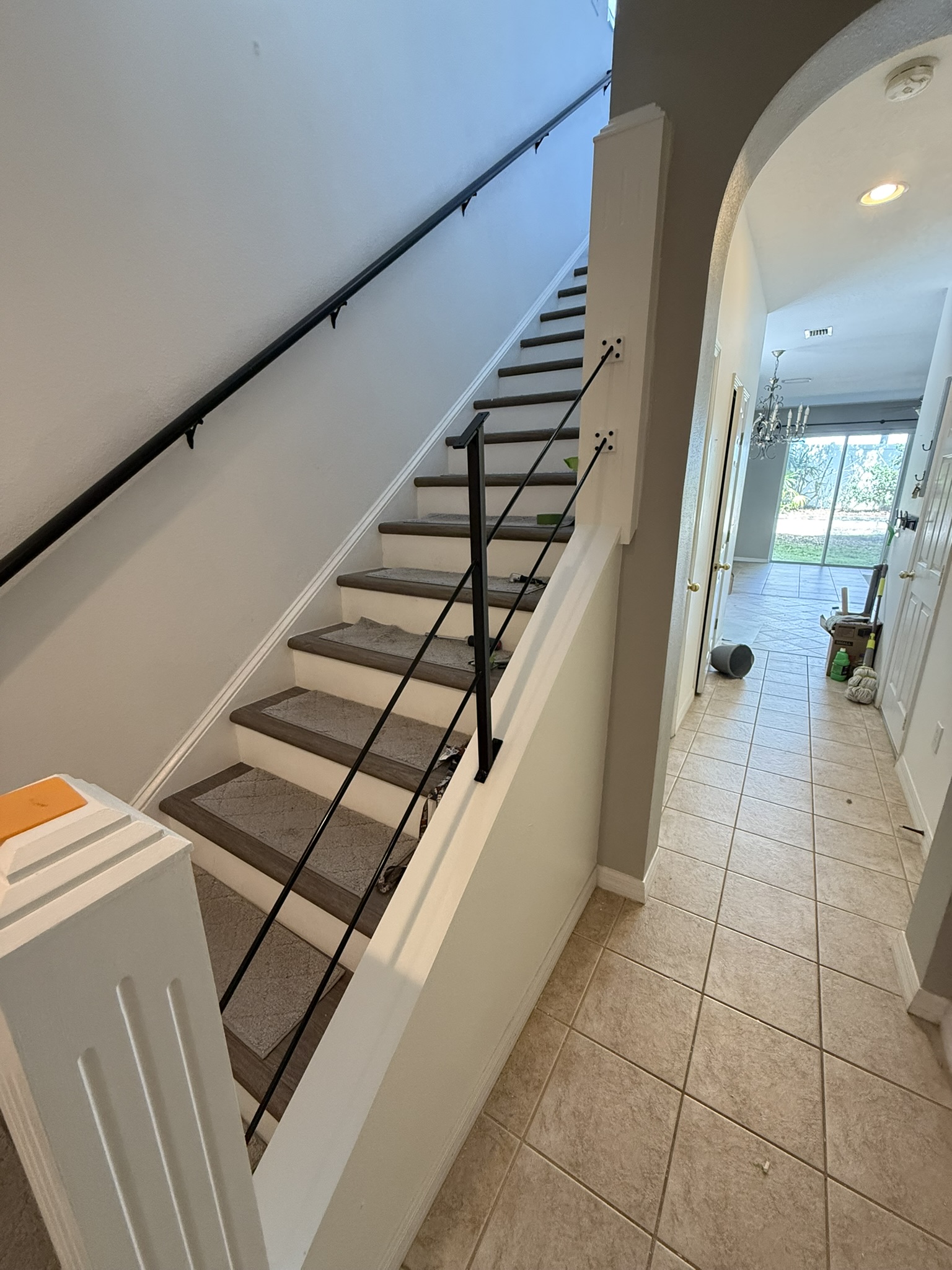 Black metal stair handrail installed on painted post